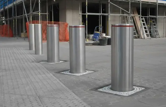 Barriers & Bollards featuring a row of retractable stainless steel security bollards installed outside a building construction site.