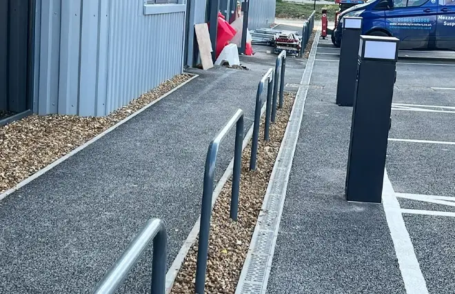 Barriers & Bollards featuring a row of galvanized steel bollards with red and white reflective bands alongside an industrial building.