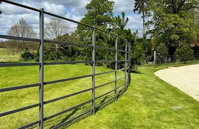 Rural & Estate Fencing featuring dark grey steel park railing fencing following a curved gravel driveway.