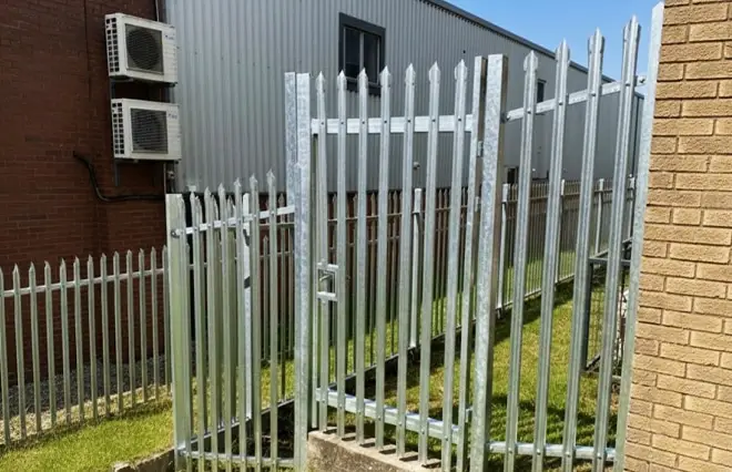 Energy Farm Fencing featuring a galvanised steel palisade security gate and perimeter fence beside a commercial building.