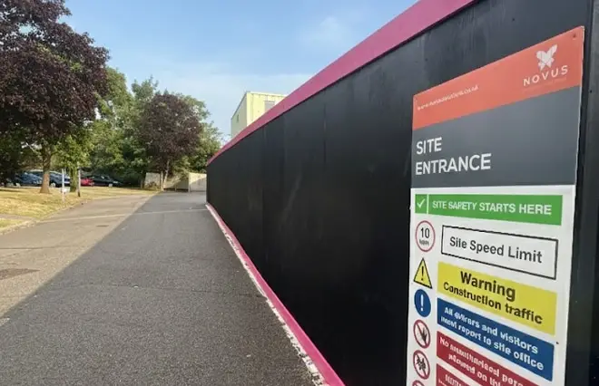 Site Hoarding featuring a black wooden security hoarding line with magenta trim and safety entrance signage.