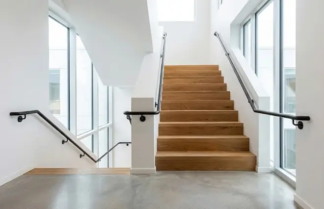 Handrails & Railings featuring wall-mounted black metal handrails along a modern interior wooden staircase.